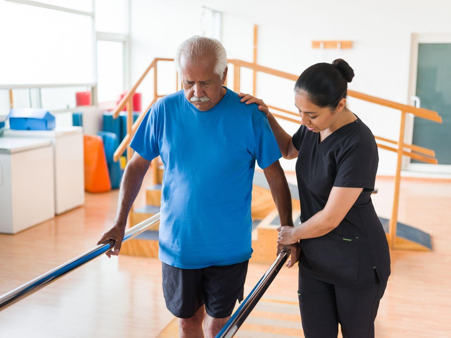 Elderly patient doing balance exercises with physiotherapist in home environment, caring and supportive setting
