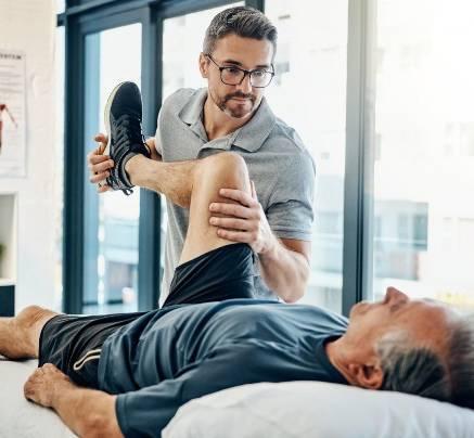 Physiotherapist performing knee rehabilitation exercises with a patient at home, professional setting