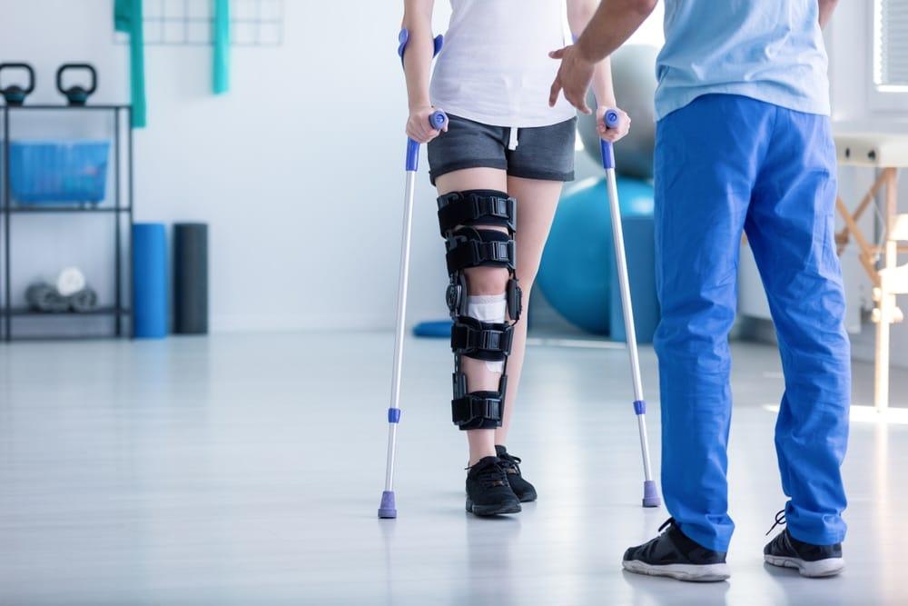 Physiotherapist guiding post-surgery patient through gentle hip mobility exercises at home, supportive care